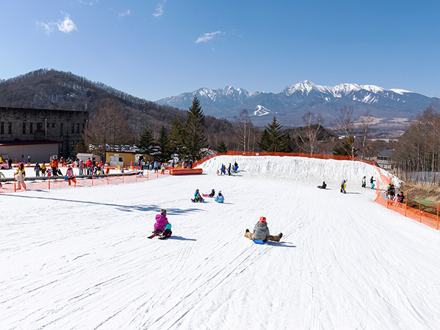 シャトレーゼスキーバレー野辺山のゲレンデ風景とソリ遊びする子どもたち
