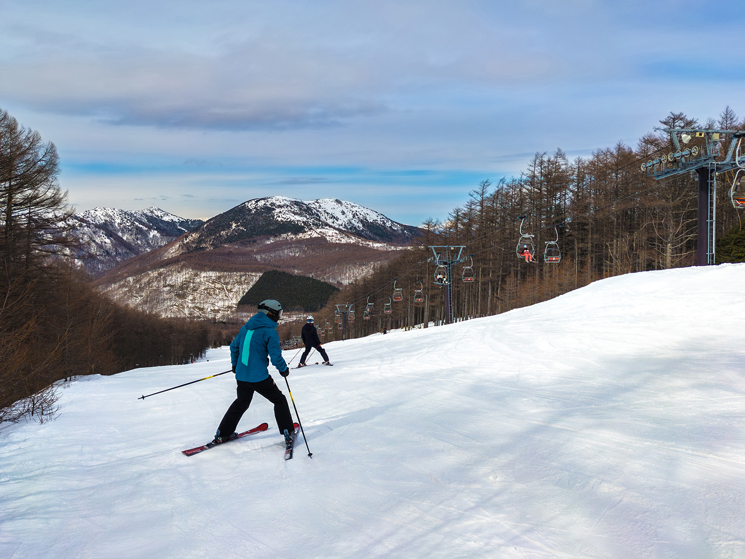 湯ノ丸山を望むスキー場のゲレンデを滑走するスキーヤー 湯の丸高原