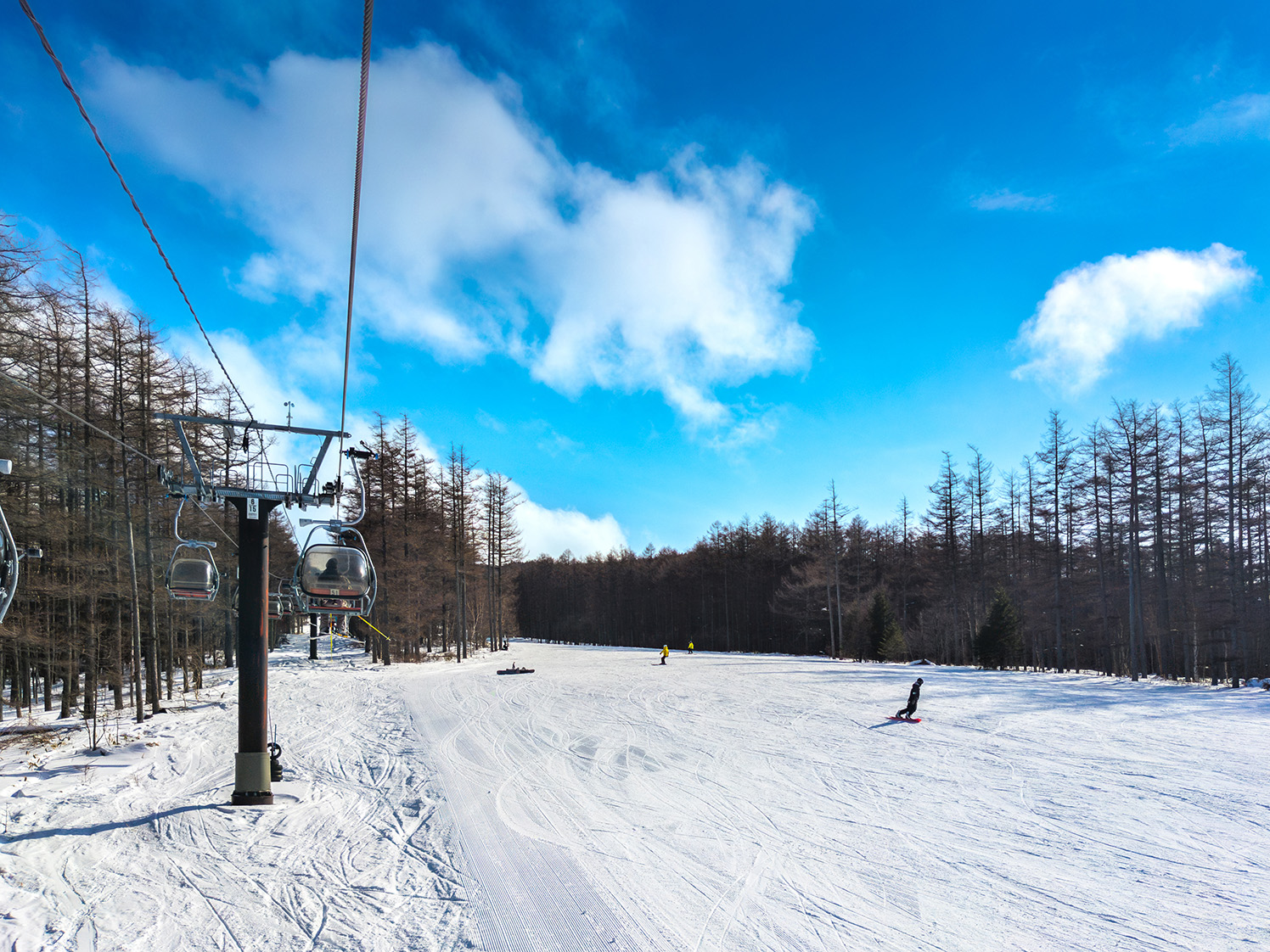 フード付きリフトから眺めるゲレンデと滑走する人々 湯の丸高原