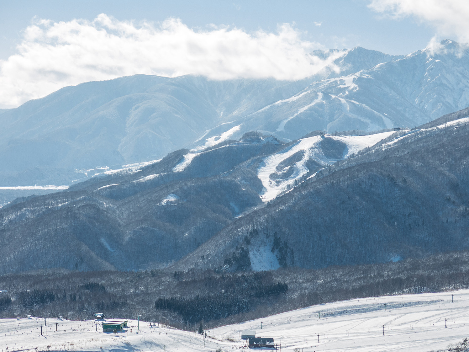 白馬乗鞍温泉スキー場のリフトとスノーボードを楽しむ人