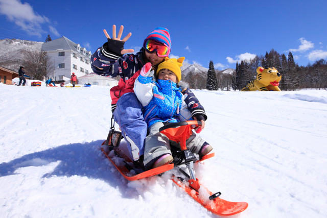 竜王スキーパークでソリを楽しむ家族